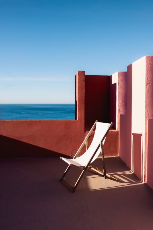 a white chair sitting on top of a balcony next to the ocean