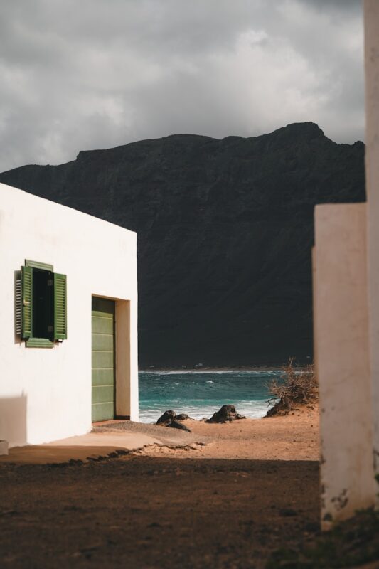 a white building with green shutters near the ocean