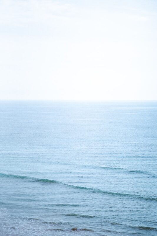 A person walking on the beach with a surfboard