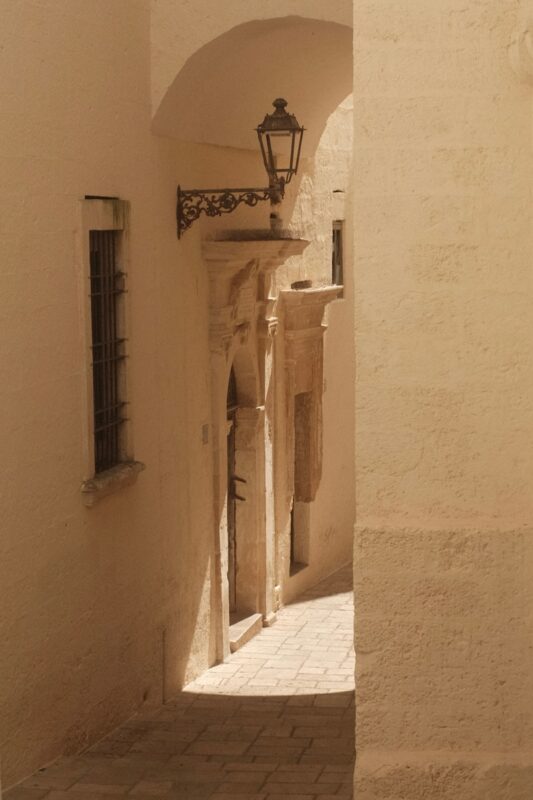 A narrow alley way with a lamp on the side